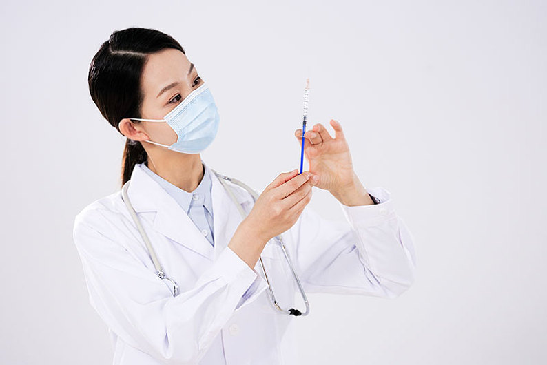 一位戴口罩的女医生使用注射器