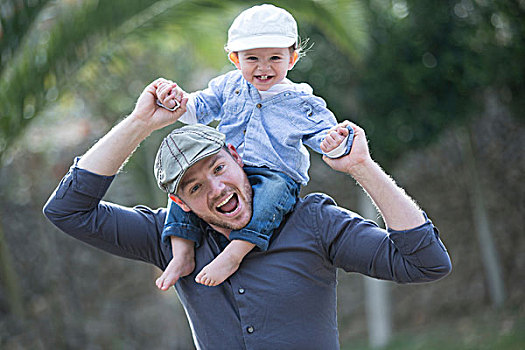 男婴,戴着,棒球帽,坐,父亲,肩部,看镜头,微笑