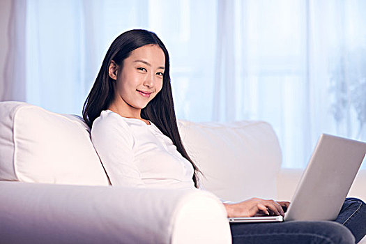 休閑女士坐在沙發(fā)上用筆記本電腦