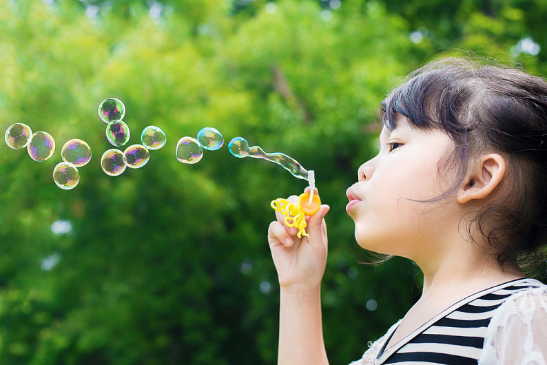 亚洲人小女孩吹肥皂泡绿色公园