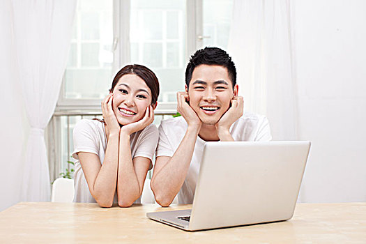 一个青年男人和一个青年女人在窗前看电脑