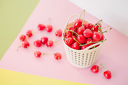 彩色背景上的白色小筐和樱桃,水果创意图片