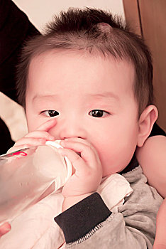 在母亲怀里喝水的一名7个月大的男婴