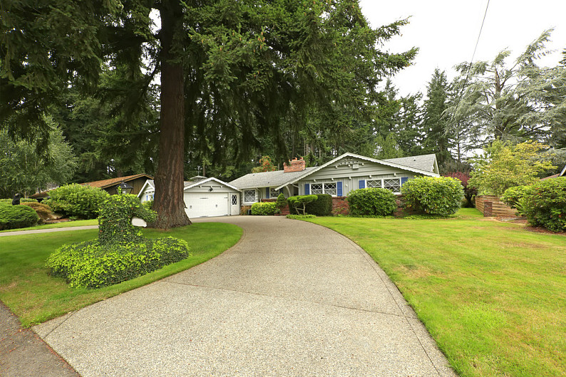 exterior with garage and driveway view, lawn with trimmed bushes