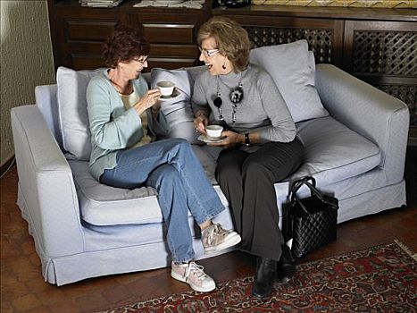 两个,老年,女人,坐,沙发,拿着,杯子,笑