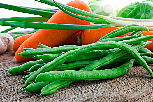 有机绿色蔬菜菜豆,是素食主义者健康重要维生素,豆子和紅蘿蔔在原木桌面上