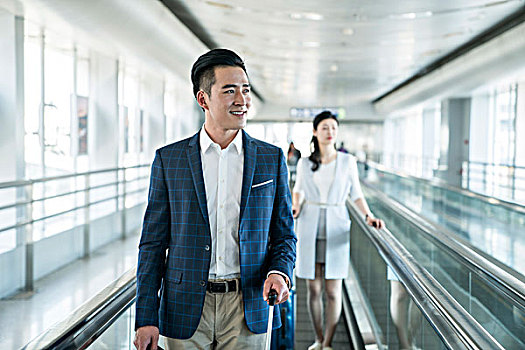 年輕商務人士在機場乘坐移動電梯