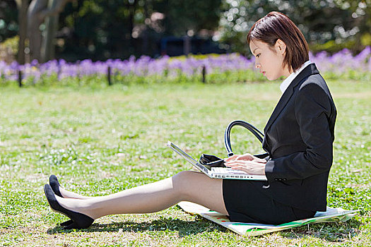 坐在草坪上上网的职业女性