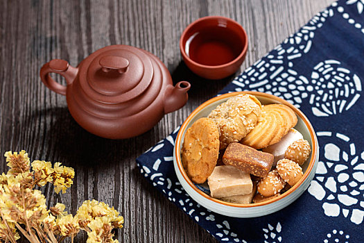 各种点心糕点茶食盛放在盘子中摆放在桌面上旁边放有紫砂壶