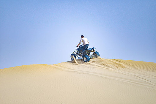 沙漠中骑沙地摩托的人