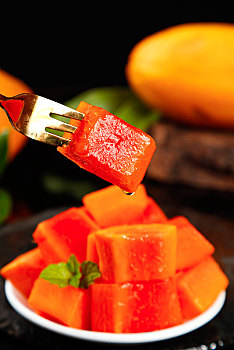 黑底上叉子叉着一块红心牛奶木瓜