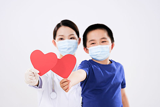 一位女医生和一个小男孩各拿着一颗红心