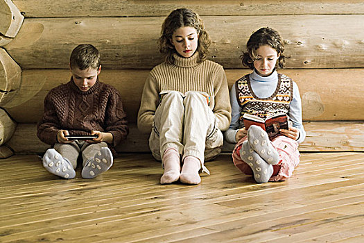 三个,年轻,兄弟姐妹,坐,并排,读,玩,电子游戏