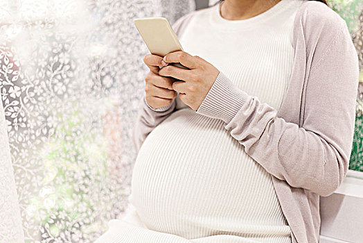 孕妇坐在椅子上使用手机