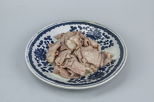 青花瓷盘上新鲜猪肉片熟食品