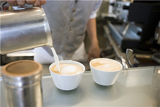 服务员,制作,两个,拿铁咖啡,倒牛奶,罐,杯子,中间部分,特写