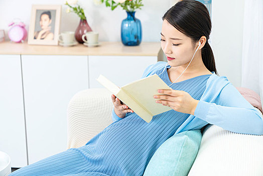 年轻孕妇在沙发上看书