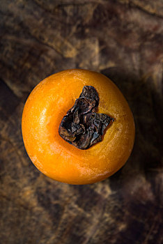 一个成熟的香蜜甜柿子摆放在陈旧的木板上