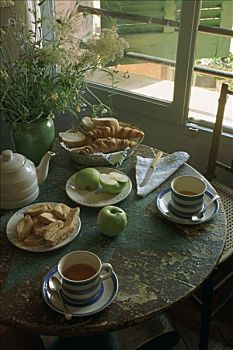 早餐桌,茶杯,面包,牛角面包,饼干,苹果,花,窗户