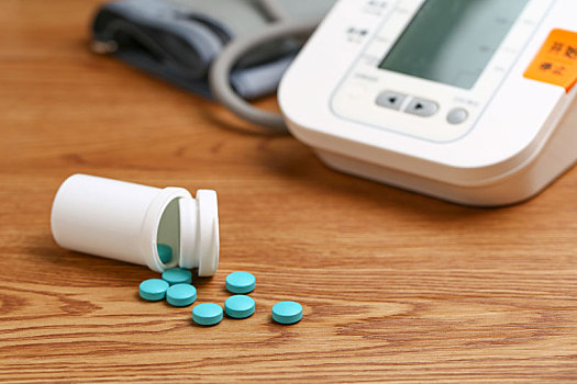 电子血压计和药瓶放在木桌上