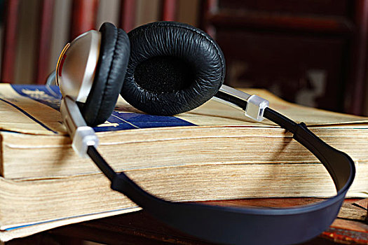 2本叠在一起很厚的旧书,头戴式耳机