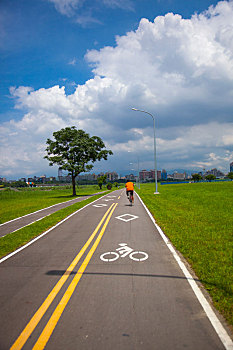 蓝天白云下的河边公园干净的自行车道