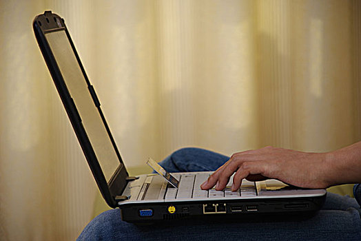 一名年轻女性坐在沙发上使用笔记本电脑