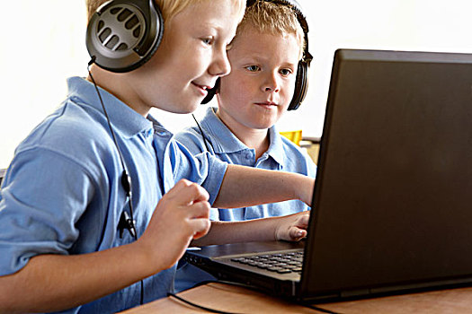 两个,男学生,穿,耳机,看电脑,显示屏