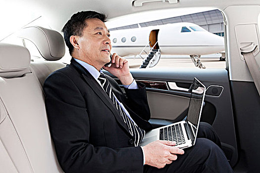 商务男士坐在轿车里打手机