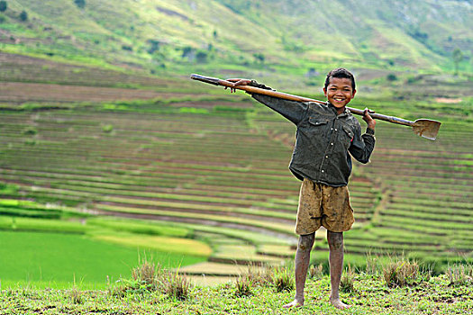 madagascar,ambalavao,young,boy,posing,in,front,of,terraced,ricefields