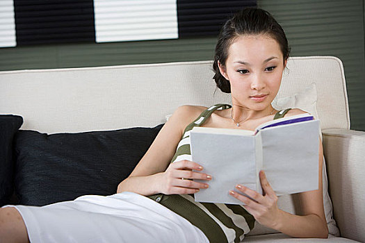 一个女人躺在沙发上看书