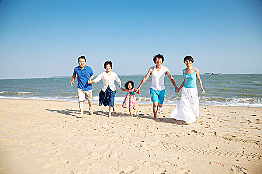一家人手牵手在沙滩奔跑