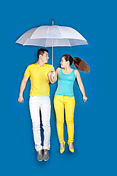 垂直拍摄蓝色背景上打雨伞的情侣