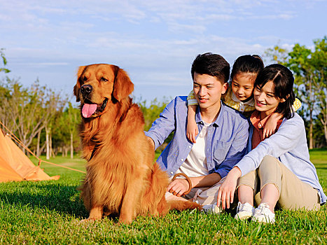 快乐的三口之家和宠物狗在公园合影