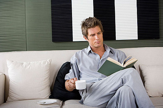 一个穿着休闲装的男人坐在沙发上看书