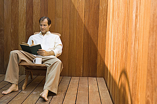 男人,坐,休闲椅,咖啡杯,读,书本
