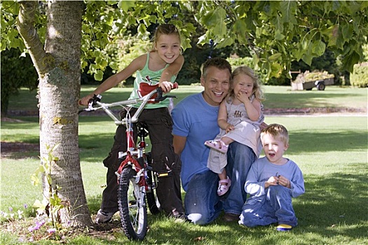 父亲,三个孩子,3-9岁,跪着,草地,旁侧,树,花园,女孩,坐,自行车,微笑,正面,头像