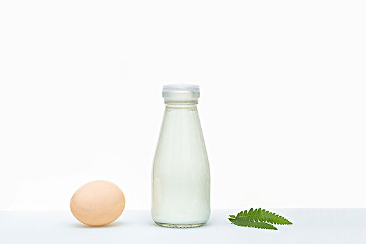 餐桌上的牛奶和鸡蛋,一片绿叶点缀