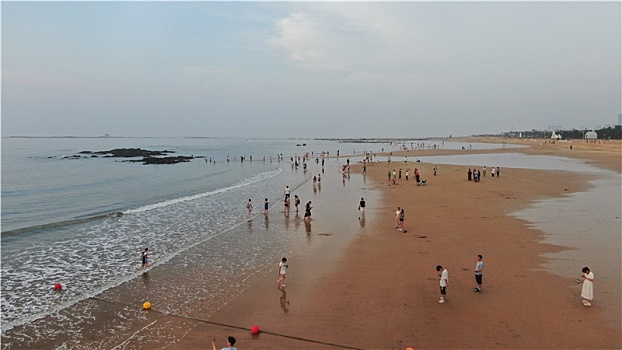 山东省日照市,清晨里的海水浴场少了人头攒动,游客悠闲漫步沙滩感受清凉