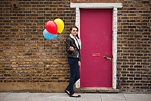 女青年,拿着,彩色,气球,砖墙