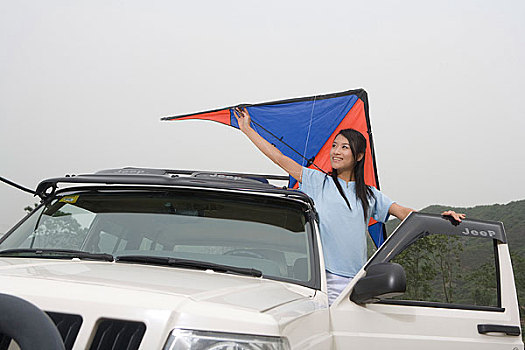 一对年轻的女孩开着越野车在郊外放风筝