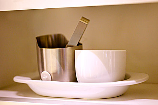 白色的茶杯和金属罐子放在托盘中