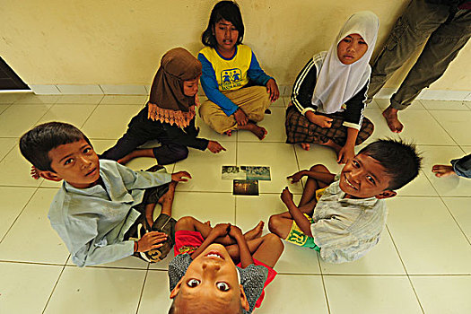 indonesia,sumatra,banda,aceh,group,of,children,looking,at,photographs,during,art,in,all,us,activities