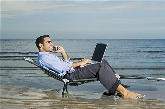 侧面,男青年,坐,休闲椅,海滩,交谈,手机,笔记本电脑