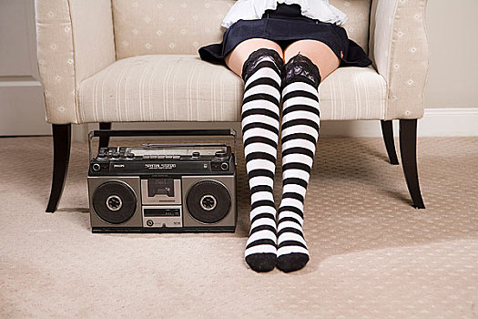 一位时尚的女人坐在沙发上地上放着一台老式收录机