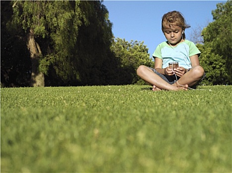 女孩,6-8岁,坐,草,公园,听,mp3播放器,正面,贴地拍摄