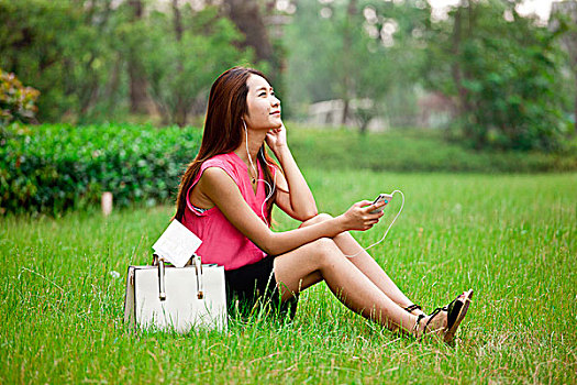 年轻女性在草地上听音乐