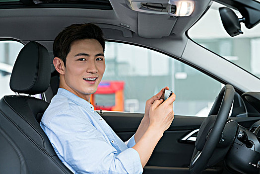 年轻商务男子在车里使用手机