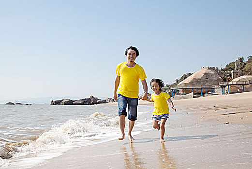 年轻父亲和女儿在海边玩耍