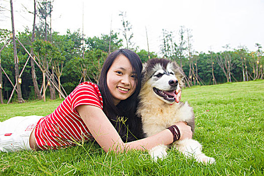 年轻的女孩和她的狗在草坪玩耍